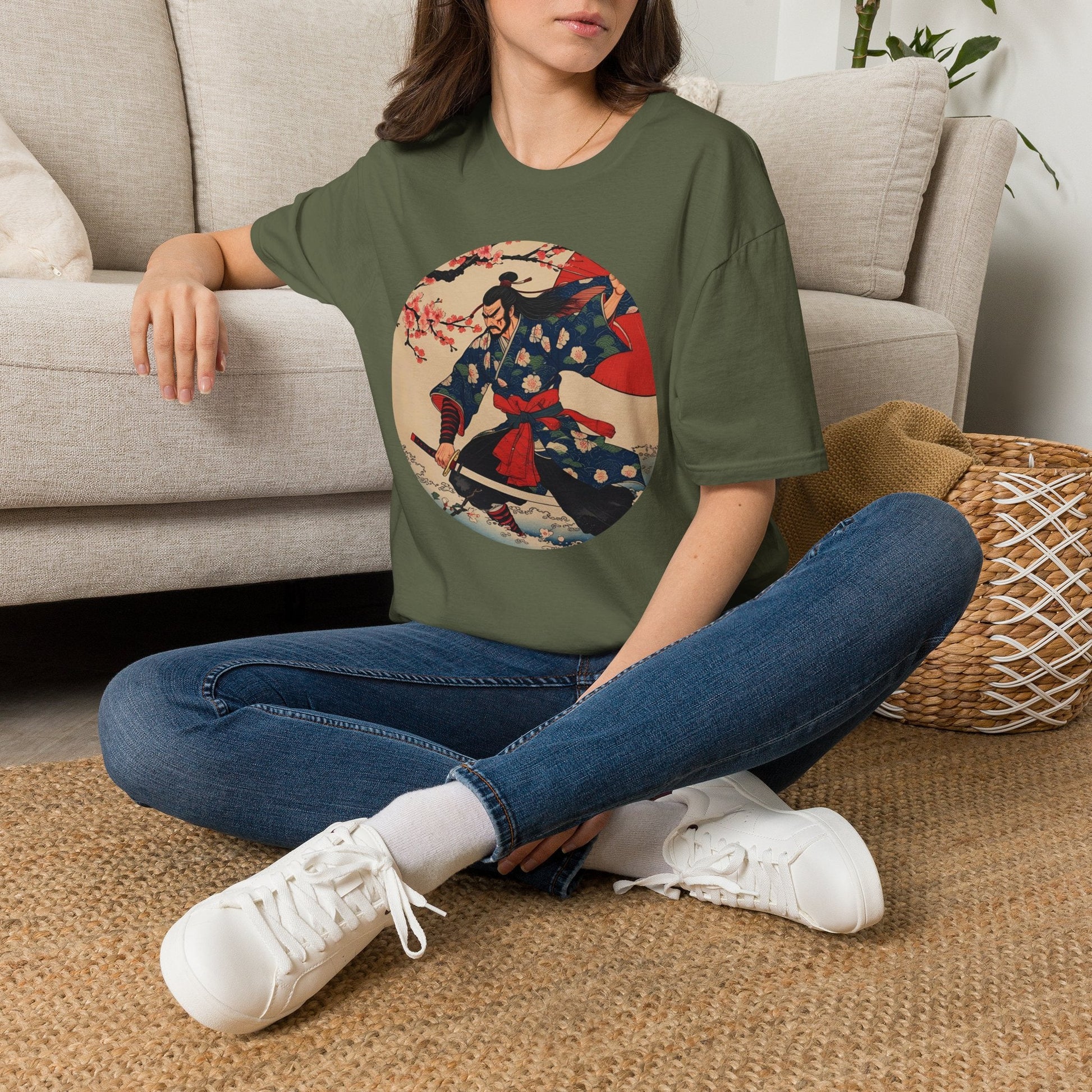Model wearing the Crimson Bloom Ronin Samurai Warrior T-Shirt in military green featuring a Japanese-inspired samurai in motion with cherry blossoms and crimson accents.
