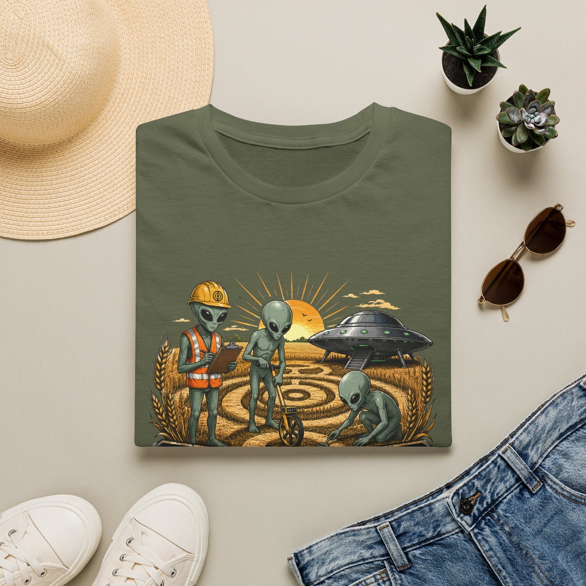 Folded Crop Circle Maintenance Crew T-Shirt in military green showing funny alien artwork with a UFO, crop circle, wheat field and bold vintage-style text.