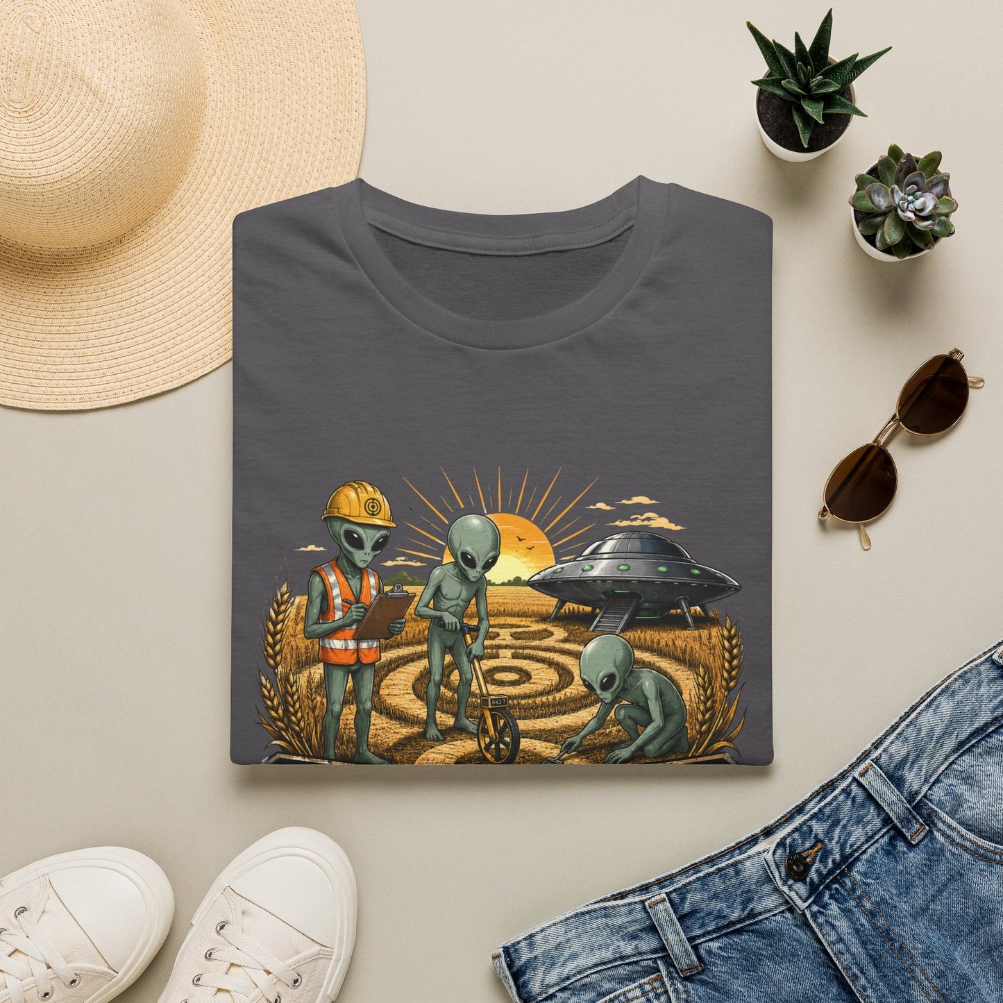 Folded Crop Circle Maintenance Crew T-Shirt in charcoal showing funny alien artwork with a UFO, crop circle, wheat field and bold vintage-style text.