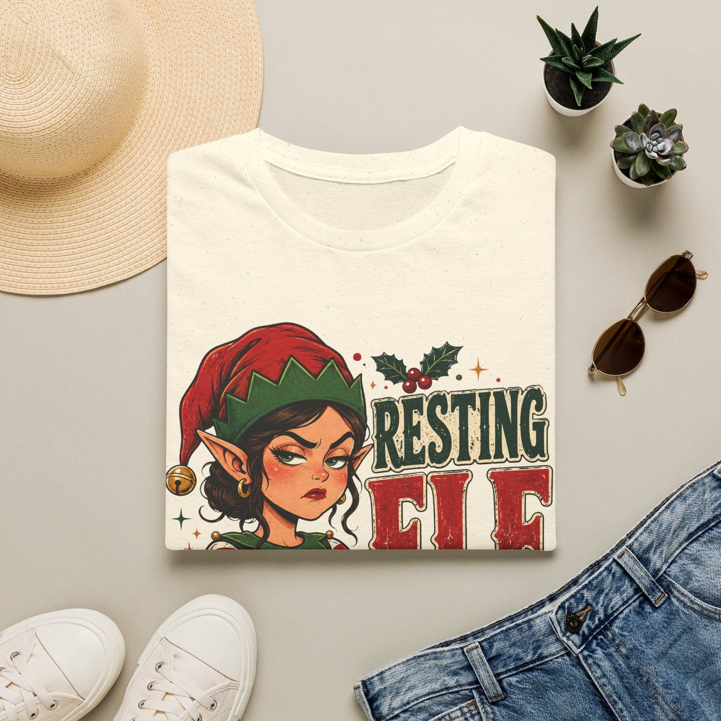 Folded Resting Elf Face Sassy Elf Christmas T-Shirt in natural showing bold festive elf design.