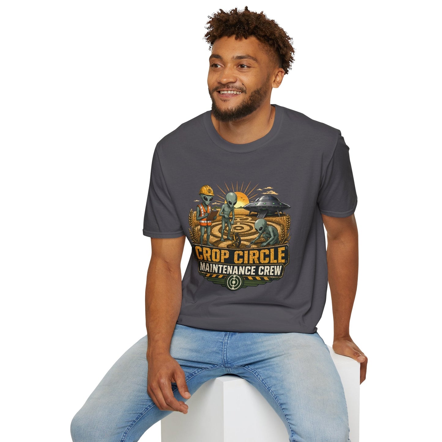 Model wearing the Crop Circle Maintenance Crew T-Shirt in charcoal featuring aliens working in a crop circle field with a UFO in the background.