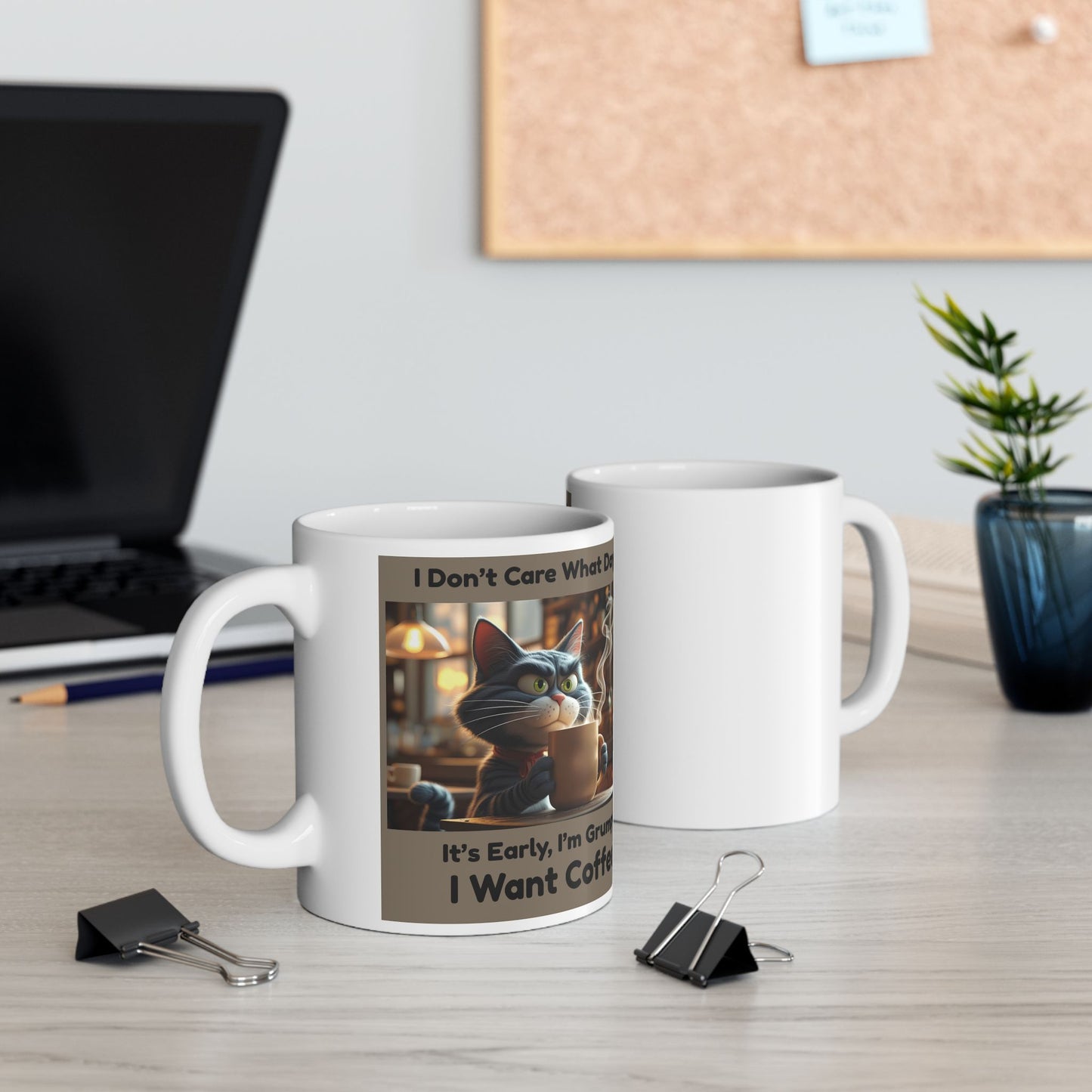 Two white mugs front and back view with a cat-themed design on a desk with office items.