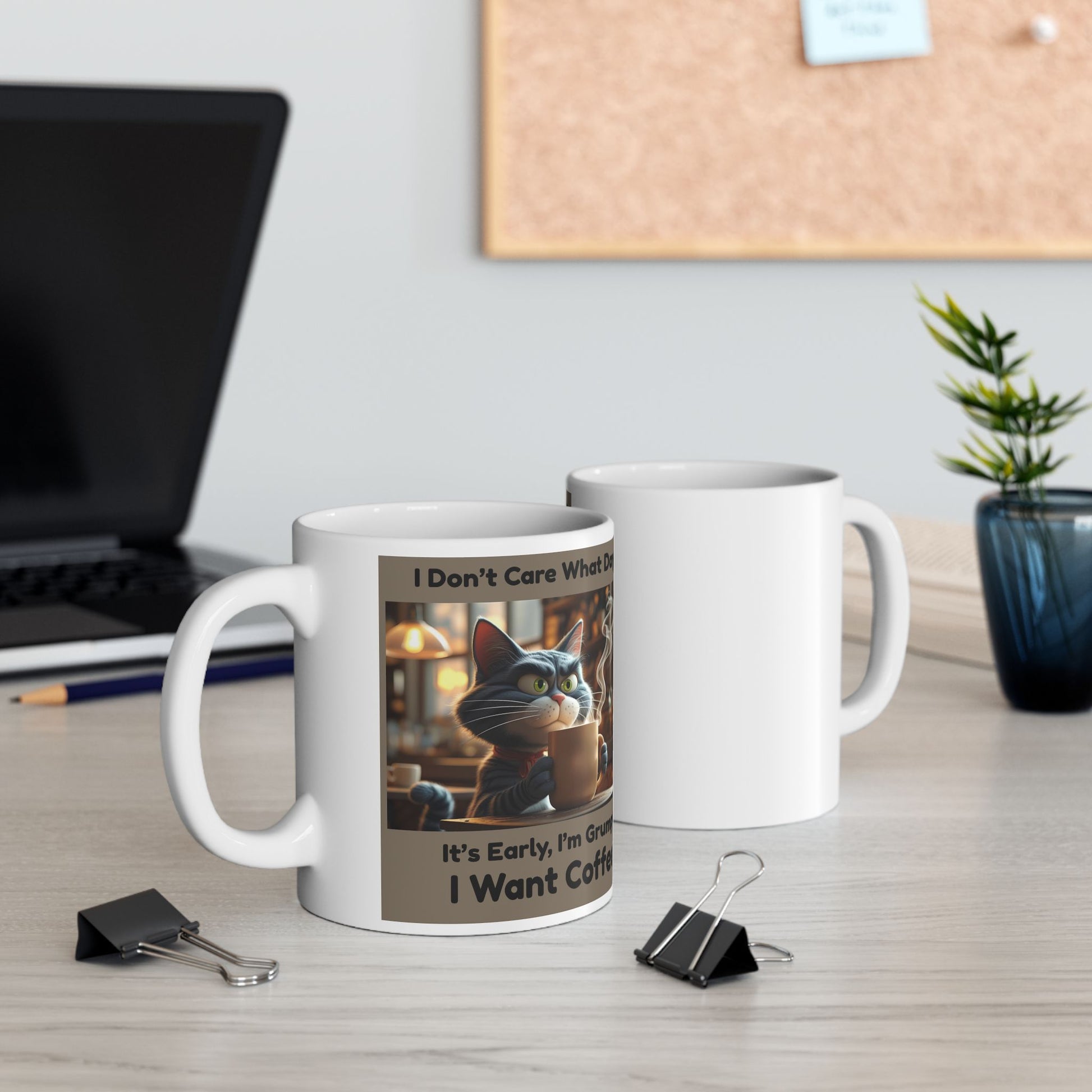 Two white mugs front and back view with a cat-themed design on a desk with office items.