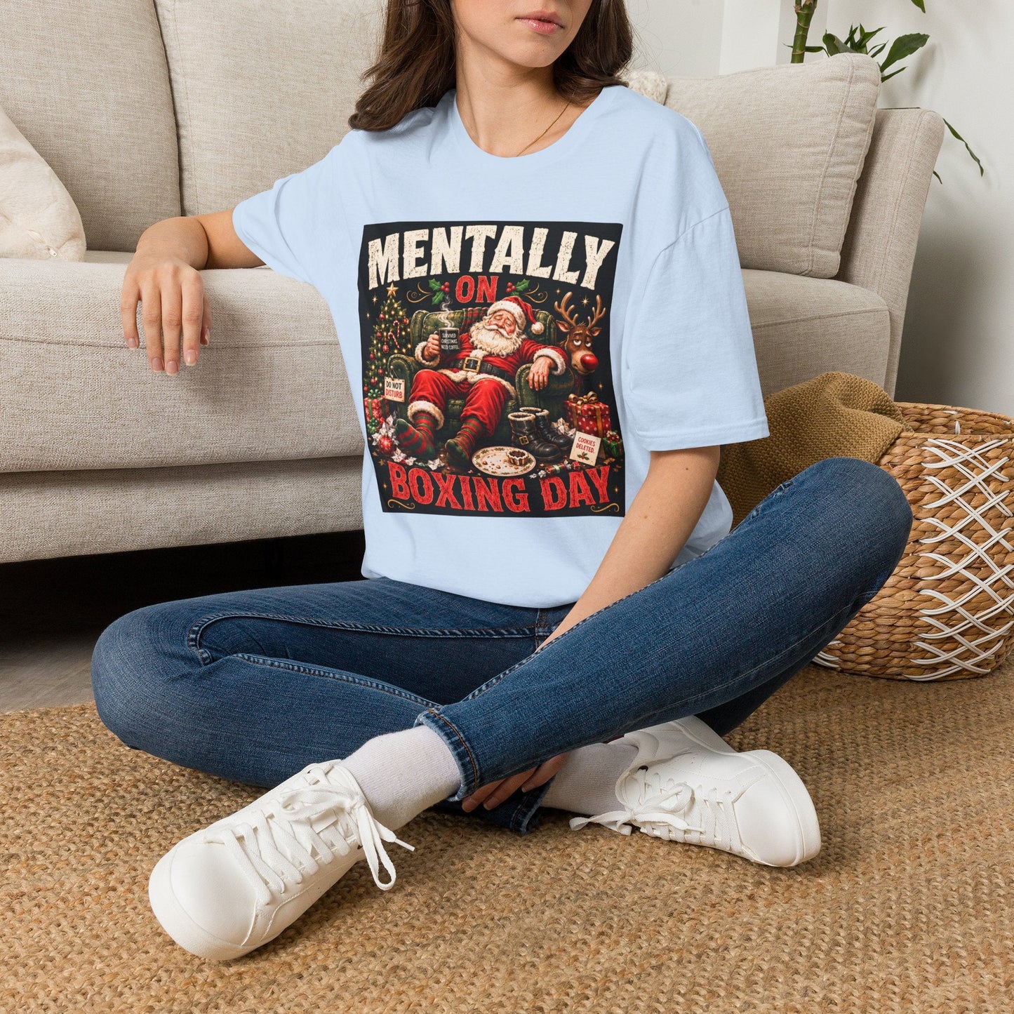 Model wearing the Mentally on Boxing Day Santa Christmas T-Shirt in light blue, with funny exhausted Santa artwork.