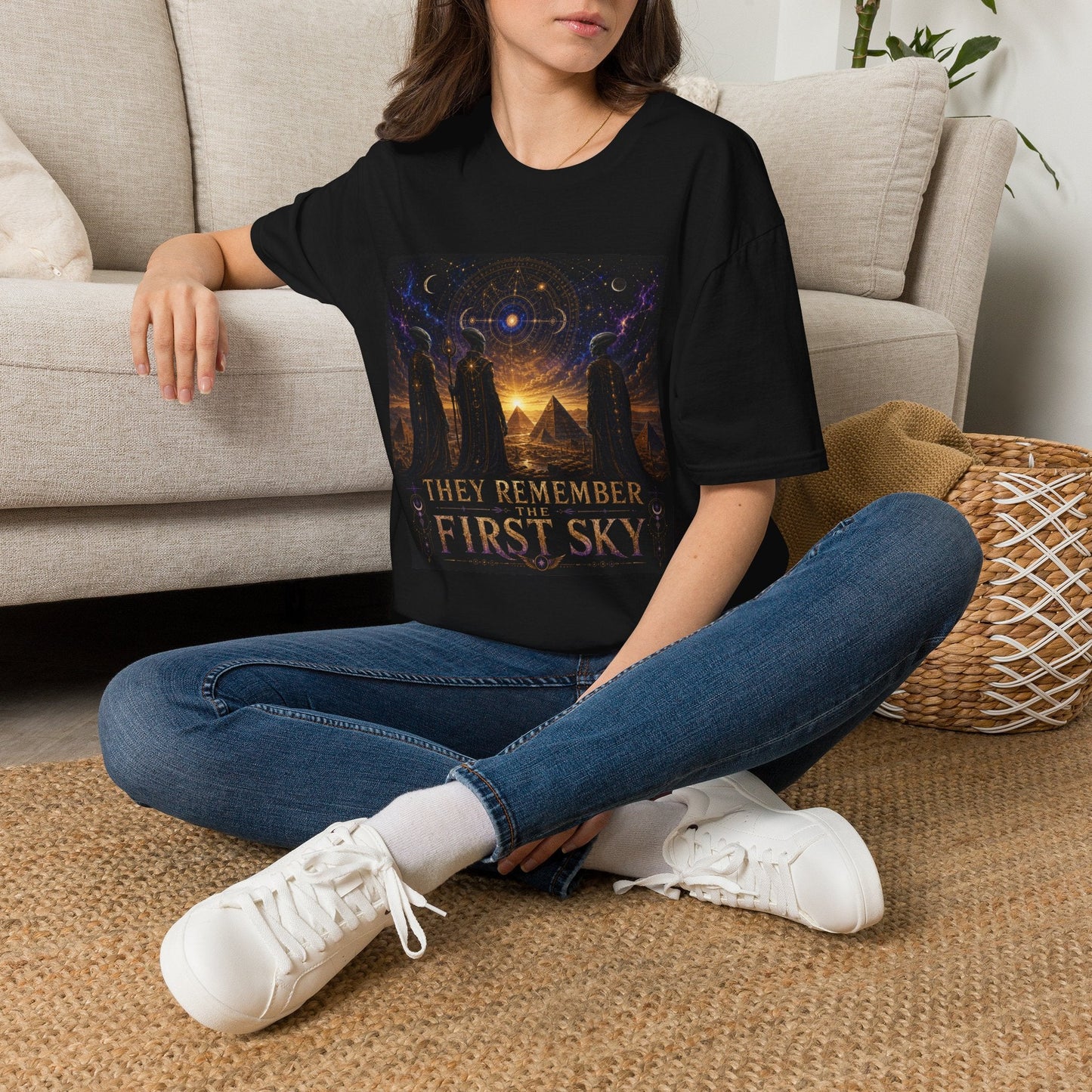 Model wearing the They Remember the First Sky T-Shirt in black featuring robed alien watchers, pyramids, and a glowing celestial sky map design.