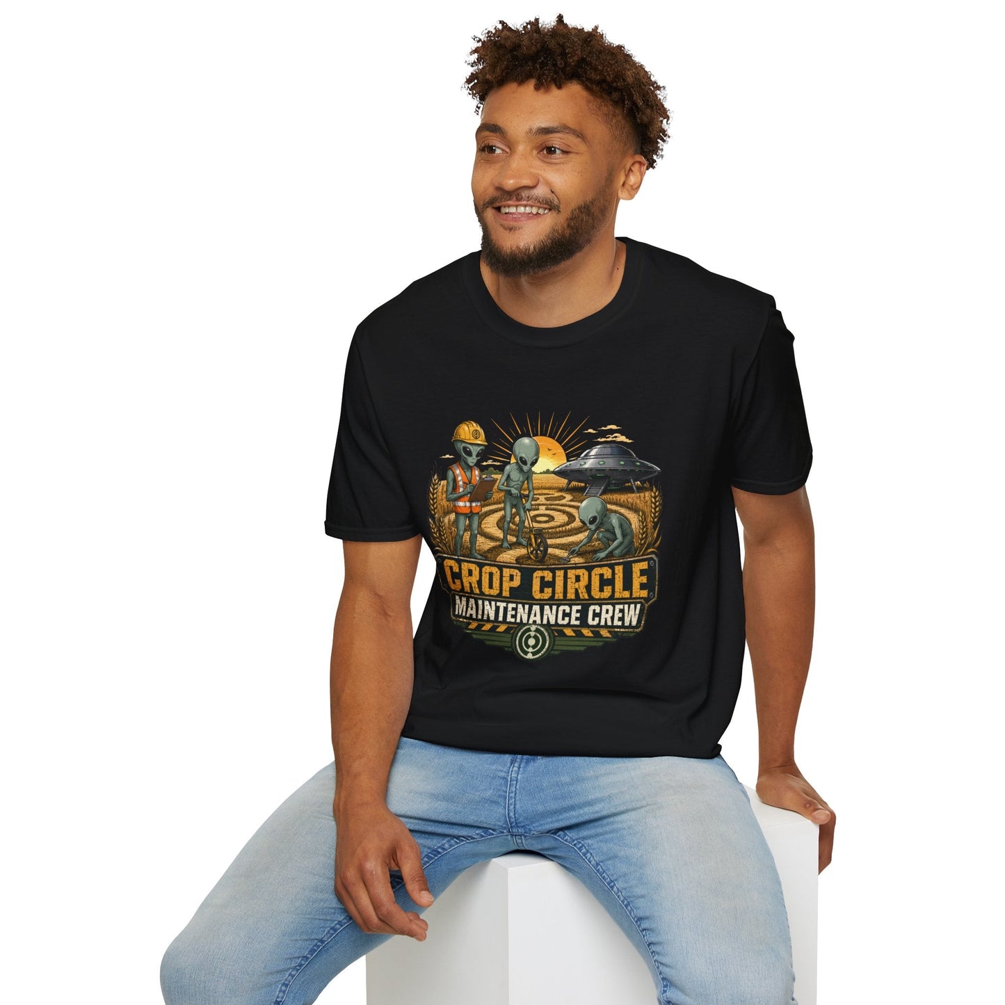 Model wearing the Crop Circle Maintenance Crew T-Shirt in black featuring aliens working in a crop circle field with a UFO in the background.